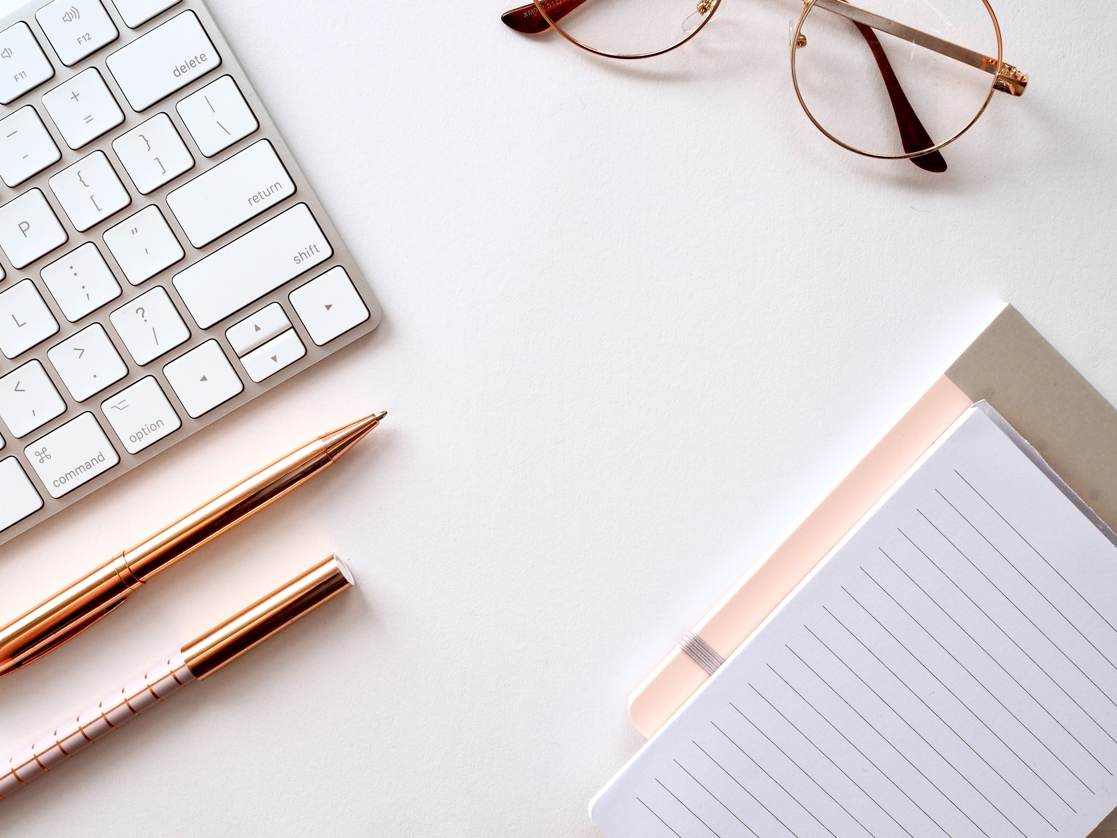 carnet de note agenda ligné avec clavier d'ordinateur et stylos et lunettes posés sur une table de bureau